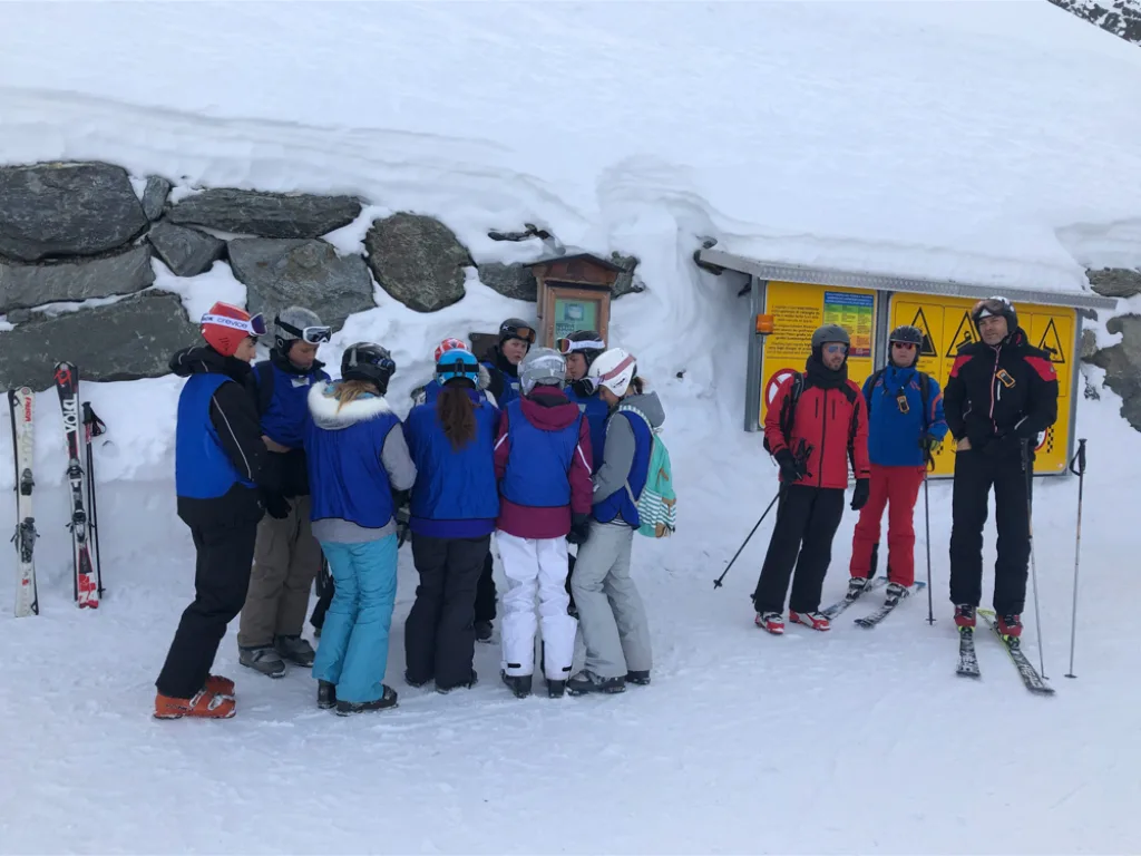 Skigruppe versammelt sich vor einer Schautafel.